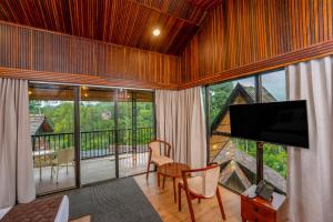 a living room with a television and a balcony at Wood Panda Luxury Resort Wayanad in Meppādi