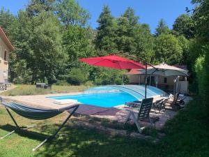 a hammock and an umbrella next to a swimming pool at Le Clapot- Les Iris in Saint-Étienne