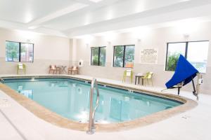 a pool in a hotel with chairs and tables at Hampton Inn & Suites Addison in Addison