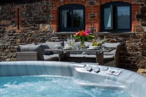 a patio with a table and a jacuzzi tub at Duchy - Treworgie Barton Cottages in Bude