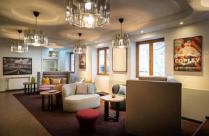 a living room with couches and chairs and chandeliers at elaya hotel hannover city, Trademark by Wyndham in Hannover