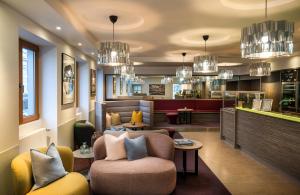 a living room with a couch and chairs and chandeliers at elaya hotel hannover city, Trademark by Wyndham in Hannover
