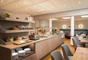 a restaurant with a counter with dishes on it at elaya hotel hannover city, Trademark by Wyndham in Hannover