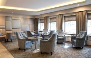 a waiting room with chairs and tables and windows at elaya hotel hannover city, Trademark by Wyndham in Hannover