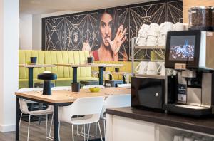 a coffee shop with tables and chairs and a poster on the wall at elaya hotel augsburg, Trademark by Wyndham in Augsburg