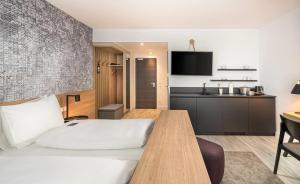 a hotel room with a bed and a kitchen at elaya hotel augsburg, Trademark by Wyndham in Augsburg +7 photos