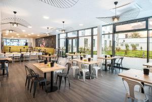 a restaurant with tables and chairs and windows at elaya hotel augsburg, Trademark by Wyndham in Augsburg