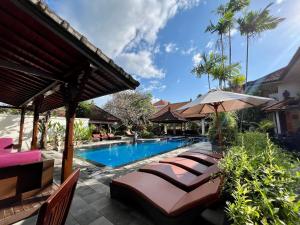 a swimming pool with lounge chairs and an umbrella at Taman Agung Hotel in Sanur