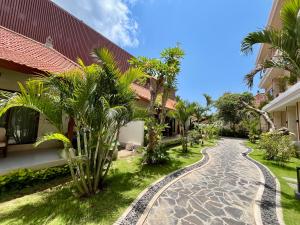 a cobblestone path in front of a building with palm trees at Taman Agung Hotel in Sanur