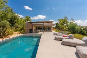 a swimming pool with lounge chairs and a house at Villa Augusta in Tourrettes