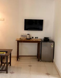 a room with a table with a television and a refrigerator at Fatima Guest House in Baga