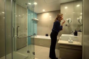 a woman standing in a bathroom brushing her teeth at Cormar Suites Kuala Lumpur in Kuala Lumpur