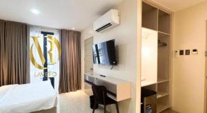 a hotel room with a bed and a desk and a tv at LAVERO SUITES in Kalibo
