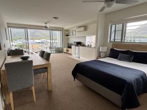 a bedroom with a bed and a table and a kitchen at Absolute Waterfront Magnetic Island in Nelly Bay +53 photos