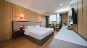 a hotel room with a bed and a flat screen tv at Bashan Hotel in Xiamen