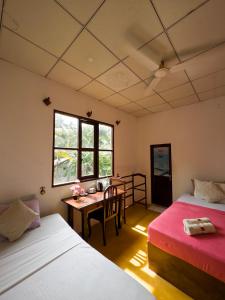 a room with two beds and a desk and a table at Splendid Lake View Safari Lodge in Udawalawe