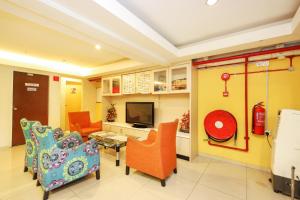 a living room with orange chairs and a tv at Hotel O Crystal City Hotel in Kuantan +18 photos