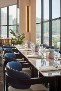 a row of tables in a restaurant with chairs and glasses at Harris Hotel & Conventions Sunshine Penang in Ayer Itam