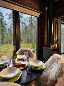 a table with plates and wine glasses and a window at Borealis Village XXL |Sauna|WiFi|Ylläs|Aurora in Äkäslompolo