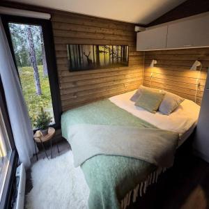 a bedroom with a large bed with a window at Borealis Village XXL |Sauna|WiFi|Ylläs|Aurora in Äkäslompolo