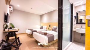 a hotel room with two beds and a sink at The Tapir Puchong by BYON Premium Suites & Hotels in Puchong