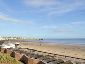 a sandy beach with a pier and the ocean at Oceans 44 in Bridlington