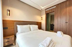 a bedroom with a large bed with white sheets and towels at Slt hola bonjour marchica in Nador