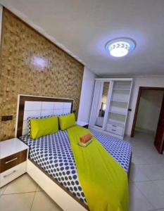 a bedroom with a bed with yellow and blue at Slt hola bonjour marchica in Nador