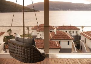 a wicker chair hanging from a balcony overlooking the water at One&Only Portonovi in Herceg-Novi