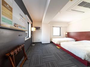 a hotel room with two beds and a large screen at SUPER HOTEL Tokyo Akabane Station Higashiguchi Ichibangai in Tokyo