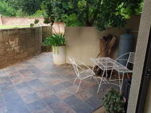 a patio with chairs and a table and a tree at ASAMé @ Oppi-Rivier in Christiana