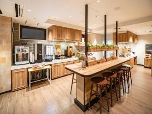 a kitchen with wooden cabinets and a large island with bar stools at SUPER HOTEL Tokyo Akabane Station Higashiguchi Ichibangai in Tokyo