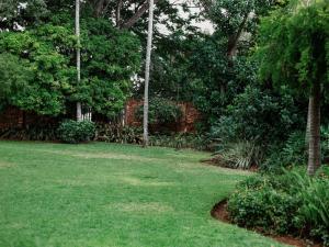 a yard with green grass and trees and a brick wall at El Palmar Guesthouse in Groblersdal +3 photos