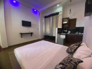a bedroom with a white bed with purple lights at Sea Tide by Jade Rock in Negombo