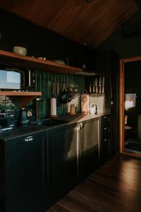 a kitchen with black cabinets and a stainless steel sink at Feelmore Tiny House Karancsalja in Karancsalja