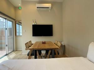 a dining room with a table and a flat screen tv at OKINAWA GREEN LODGE in Okinawa City