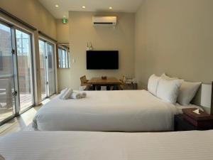 a bedroom with two beds and a flat screen tv at OKINAWA GREEN LODGE in Okinawa City