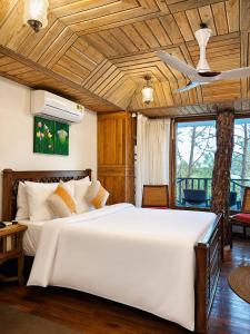 a bedroom with a large white bed with a wooden ceiling at Chillaru Spa & Resort in Kasauli +84 photos