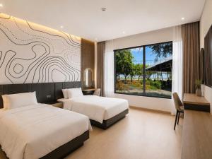 a bedroom with two beds and a large window at Dragon Hotel in Rạch Giá