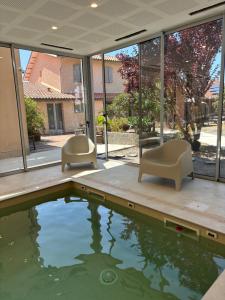 a swimming pool with two chairs and a table at LOGIS HOTELS - Hôtel et Restaurant L'Océana in Lanton