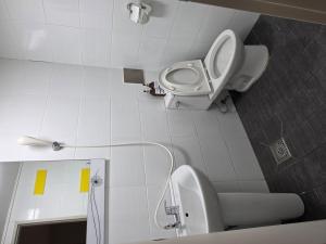 a white bathroom with a toilet and a sink at Welcome Busan Guesthouse in Busan +2 photos
