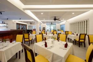a restaurant with white tables and yellow chairs at THE RIVERFRONT CENTRAL Hotel in Siem Reap