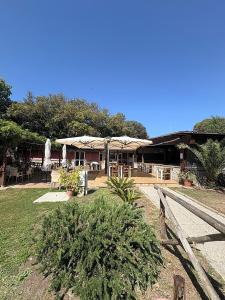 a building with tables and umbrellas in a yard at Camping Internazionale Di Castelfusano in Lido di Ostia