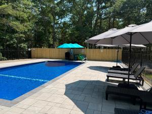 a swimming pool with two umbrellas and two chairs at Hinckleys Dreamwood Cottages in Bar Harbor
