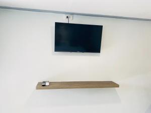 a tv hanging on a wall with a wooden shelf at Seattle Samaesarn Resort in Ban Samae San
