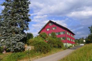 a red barn on the side of a road at Haus zum Kranich, traditionelles, charmantes, ehemaliges Bauerngasthaus in Möggers