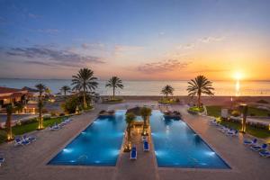 an overhead view of two pools with palm trees and the ocean at Barracuda Resort in Umm Al Quwain