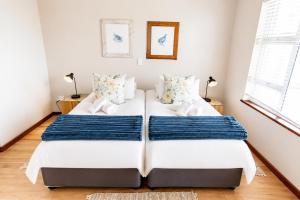 two beds in a bedroom with white walls and wood floors at Jetty Seaview Apartment in Swakopmund