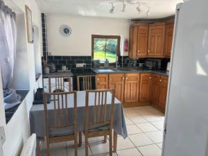 a kitchen with wooden cabinets and a table and chairs at Tor Cefn in Kidwelly
