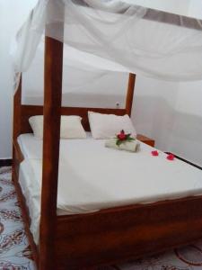 a bed with white sheets and red roses on it at Casa twende A in Nungwi